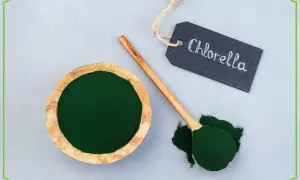 Chlorella tabletki na co pomaga? Zielony proszek w misce i na łyżce, obok tabliczka z napisem "Chlorella".