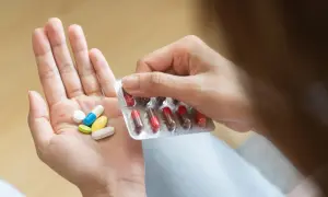 Dłoń z garścią tabletek i blistrem. Wśród nich jest też kwas foliowy, ważny dla zdrowia.