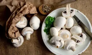 Świeże pieczarki na talerzu i w papierowej torbie. Poznaj ich bogate pieczarki wartości odżywcze.