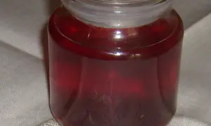 Słoik z ciemnoczerwonym, domowym octem z czarnej porzeczki, gotowym do użycia w kuchni.