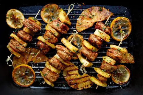 Szukasz odpowiedzi na pytanie: czy grill jest zdrowy? Oto apetyczne szaszłyki z mięsa i ananasa z grillowaną cytryną, które mogą być częścią zdrowej diety.