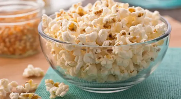 Misternie ułożony popcorn w szklanej misce. Czy popcorn jest zdrowy? To zależy od sposobu przygotowania, ale sam w sobie jest dobrym źródłem błonnika.