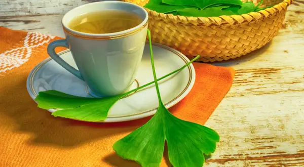 A filiżanka herbaty z miłorzębu japońskiego, liście miłorzębu w koszyku i na talerzyku.