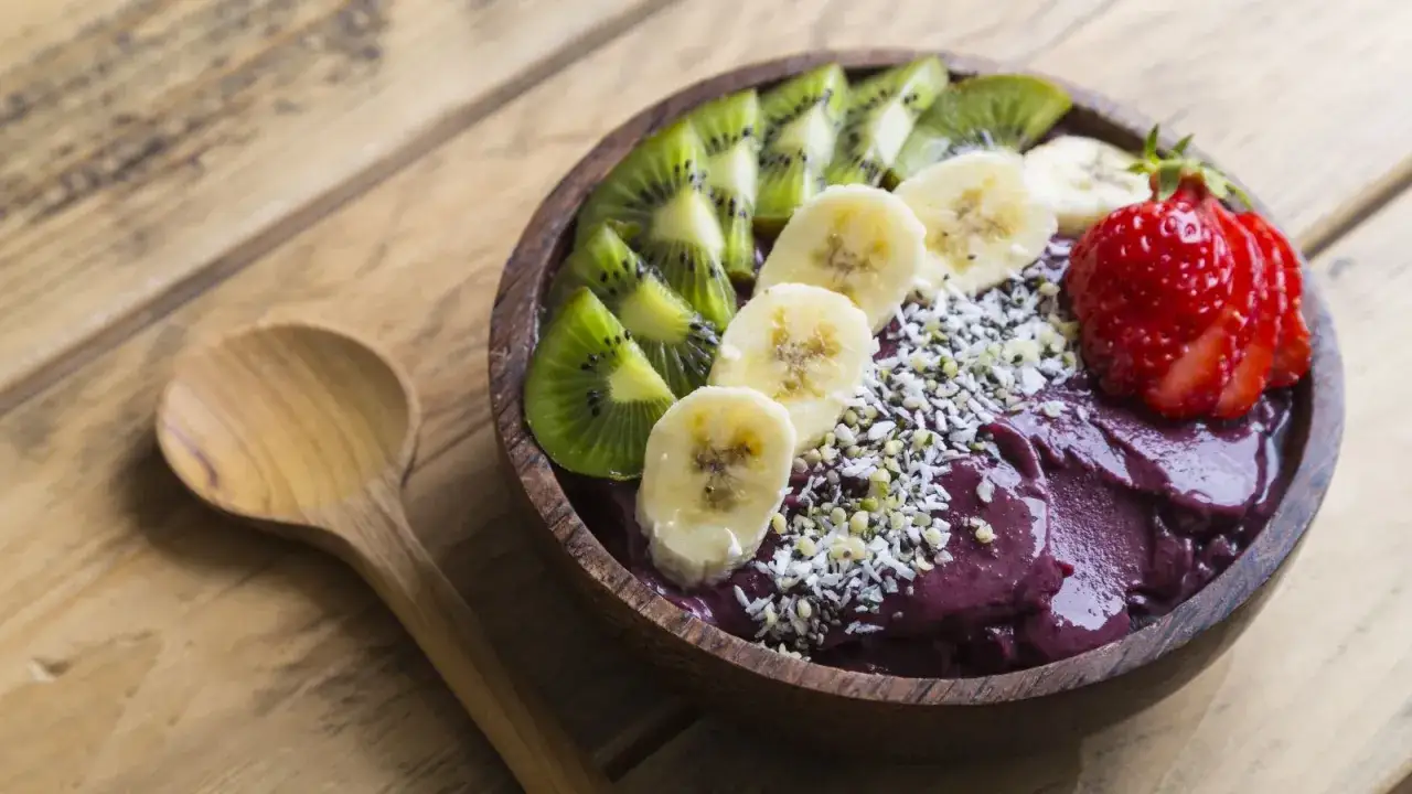 Miska pełna smoothie z owoców acai, ozdobiona plasterkami banana, kiwi i truskawką. Idealne śniadanie, by dowiedzieć się, acai co to jest.