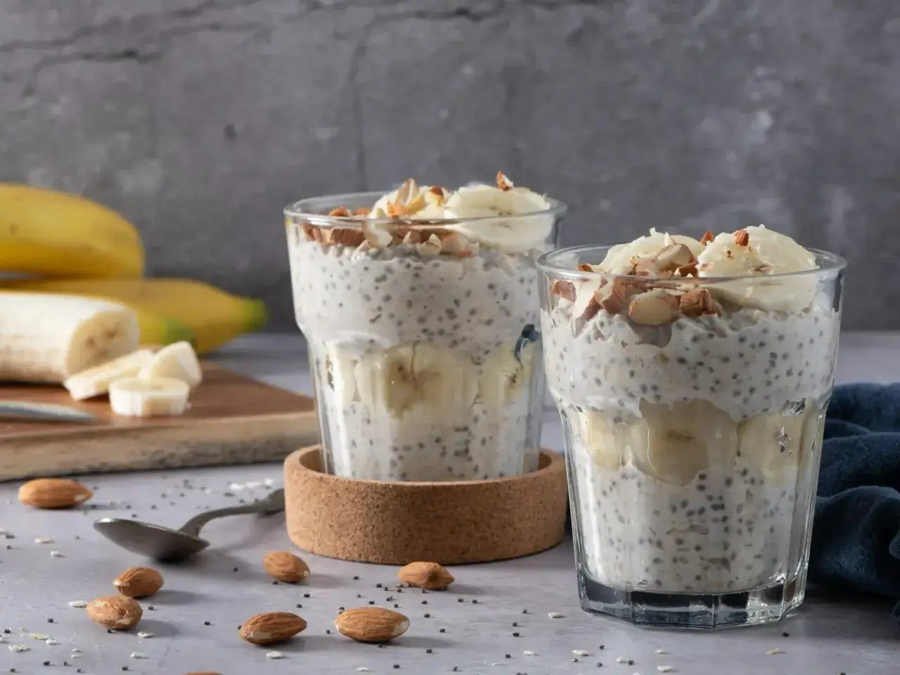 Dwa pucharki z puddingiem chia z bananem i migdałami. Czy owsianka jest zdrowa? Ten deser z pewnością tak!