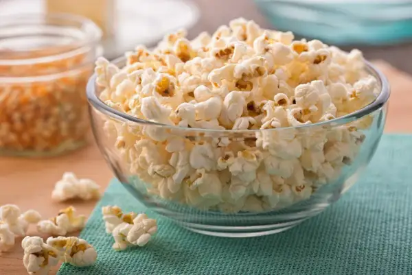 Misternie ułożony popcorn w szklanej misce. Czy popcorn jest zdrowy? To zależy od sposobu przygotowania, ale sam w sobie jest dobrym źródłem błonnika.