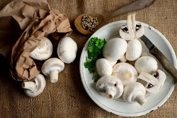 Świeże pieczarki na talerzu i w papierowej torbie. Poznaj ich bogate pieczarki wartości odżywcze.